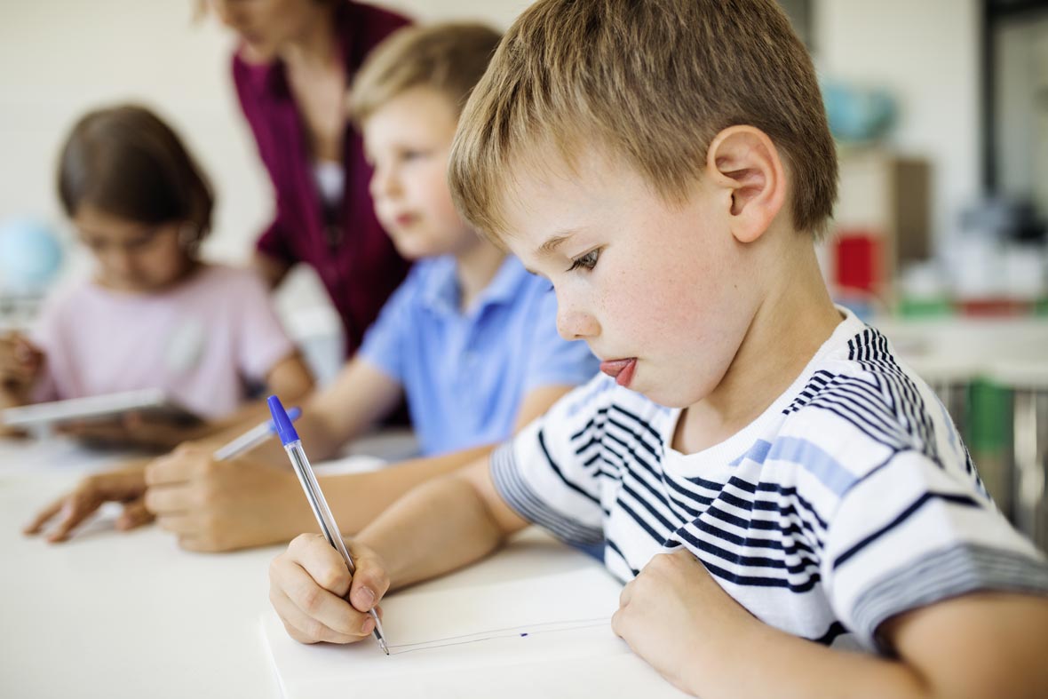 Ein Junge schreibt konzentriert in der Schule, nachdem er in der Physiotherapie Vier Tore Reha in Neubrandenburg aufgrund seiner Lernprobleme behandelt wurde.